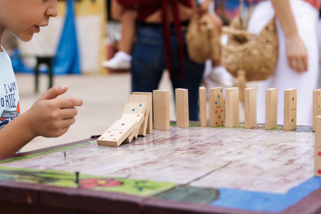 Boy playing with a wooden dominoes outside, in a medieval market
